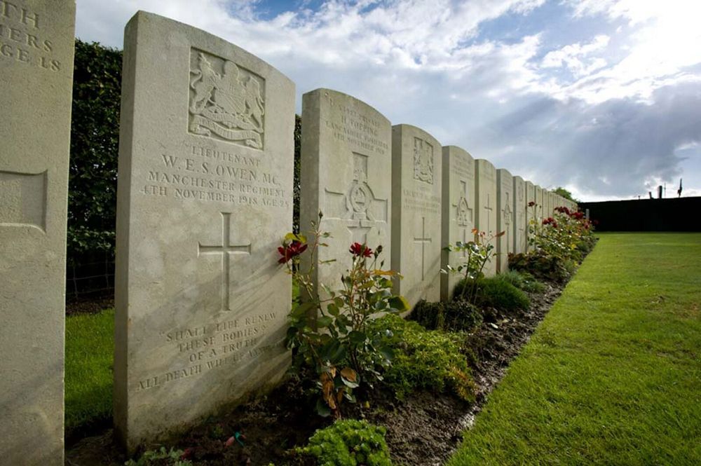 Wilfred Owen headstone amidst a row of other CWGC headstones at Ors Communal Cemetery.