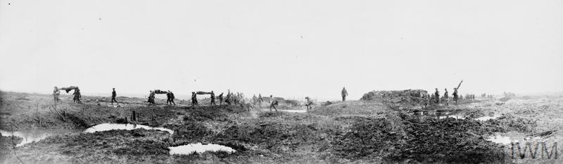 Canadian strecher bearers silhouetted against the sky carry wounded troops across muddy ground. Shell craters are filled to the brim with murky rainwater.