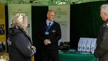 People chatting at a Commonwealth War Graves stall at an event.