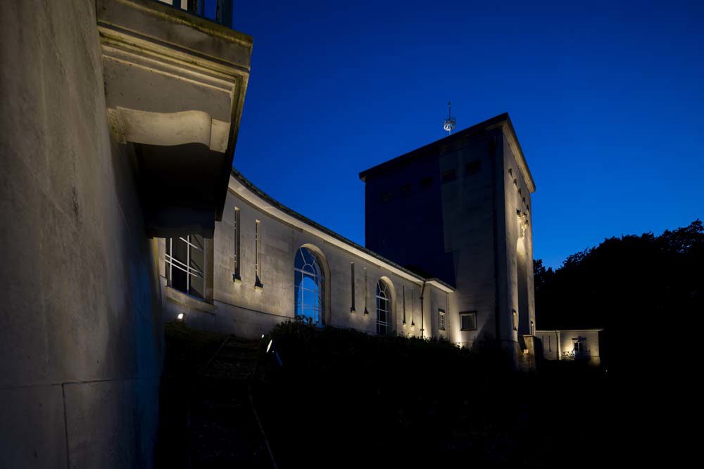 Runnymede Memorial central tower and wings illuminated by floodlights against a deep royal blue night sky