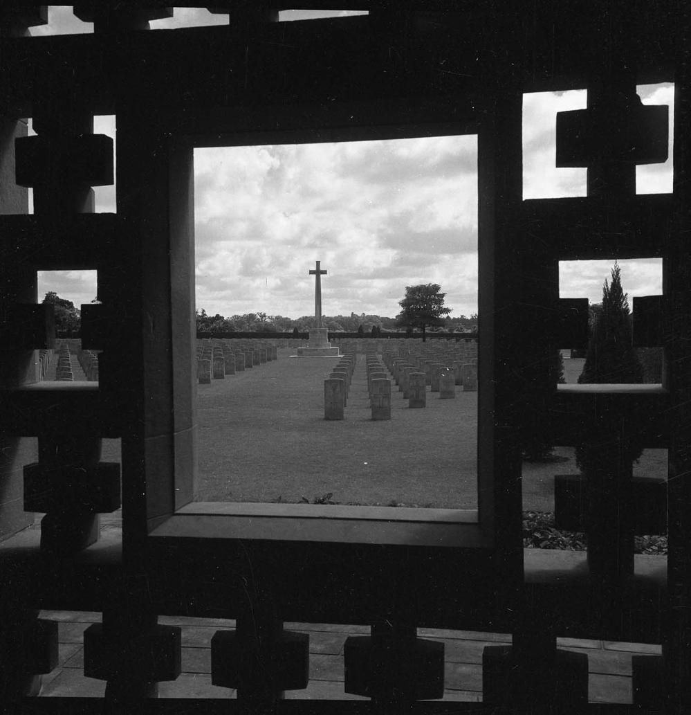Black and white photo of Ranchi War Cemetery India with the Cross of Sacrifice framed through a window of the main shelter building.