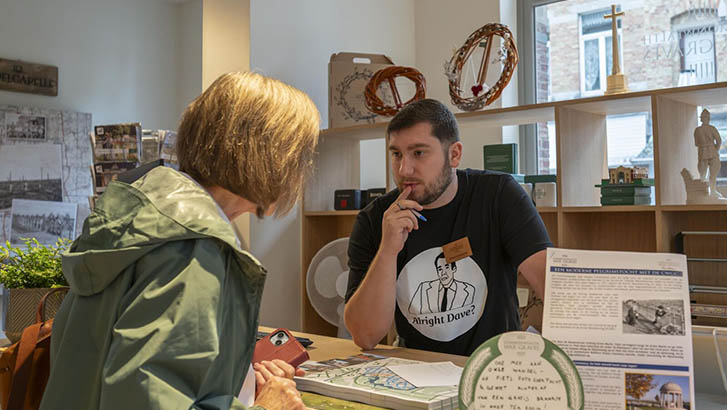 A man chats to a women over the counter of a shop.